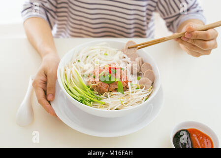 Frau essen traditionellen vietnamesischen Pho Nudeln mit Stäbchen. Stockfoto