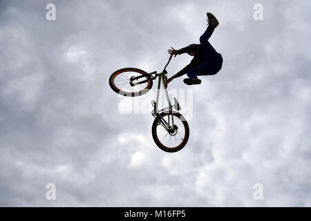 Die Silhouette eines jungen Mannes freestyle stunt Radfahrer in den Himmel darstellenden Stunt springen von einem Skatepark Rampe fliegen Stockfoto