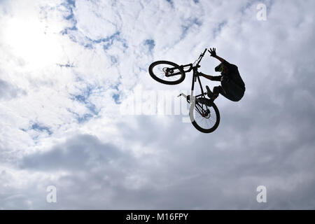 Die Silhouette eines jungen Mannes freestyle stunt Radfahrer in den Himmel darstellenden Stunt springen von einem Skatepark Rampe fliegen Stockfoto