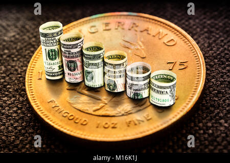 Nahaufnahme des goldenen Krügerrand Münze mit einem Diagramm Reflexion auf seiner Oberfläche mit grünen und roten Balken und Walzen der Dollar Banknoten bilden declinig Schritte Stockfoto