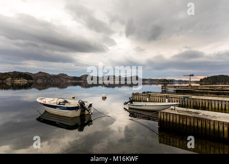 Forresfjorden, Karmoy in Norwegen - Januar 10, 2018: Ein kleines Motorboot im Wasser ruhen von einem Pier in den Fjord Forresfjorden. Schönen Himmel und blaues Licht Stockfoto