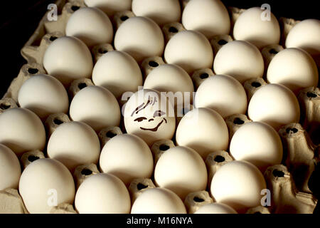 Frohe Eier in einer Schale mit Eiern. Sich wiederholende Muster. Ei in ein Fach von Eiern. Stockfoto