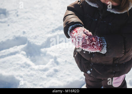 Ein 3-jähriges Kind tragen Winterkleidung, winter Fäustlinge, spielt im Schnee an einem sonnigen Wintertag in den Vereinigten Staaten. Stockfoto