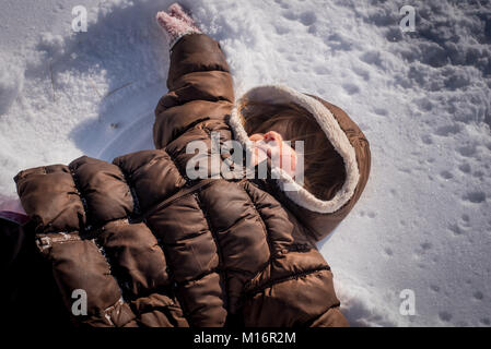 Ein 3-jähriges Mädchen macht einen Schnee Engel im Schnee im Nordosten der Vereinigten Staaten von Amerika. Stockfoto