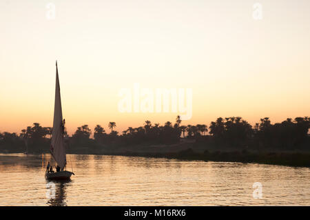 Traditionelle felucca Ketsch Segeln auf dem Nil bei Sonnenuntergang, Luxor, Ägypten Stockfoto