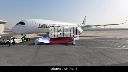 Doha, Katar. 27 Jan, 2018. Qatar Airways Mitarbeiter halten eine nationale Flagge Katar neben einem Airbus A350-1000 Jet am internationalen Flughafen von Doha in Doha, der Hauptstadt von Katar, Jan. 27, 2018. Die Marke neue Flugzeuge, die in Doha im Rahmen der Demonstration Tour 12 Naher Osten und Asien-Pazifik-Destinationen angekommen. Credit: Nikku/Xinhua/Alamy leben Nachrichten Stockfoto