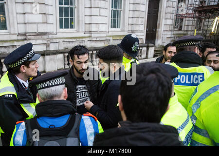 London, Großbritannien. 27. Januar, 2018. Polizisten nehmen Adresse von einem Mann wegen des Verdachts auf eine Straftat nach Paragraph 13 des Terrorismus handeln, nachdem eine verbotene Flagge während eines Protestes von Mitgliedern der kurdischen Gemeinschaft gegenüber Downing Street gegen die militärische Offensive der Türkei in und um kurdische Geflogen-gesteuerte Afrin in Syrien und gegen eine Erklärung der britische Außenminister Boris Johnson zur Unterstützung der Türkei festgehalten. Credit: Mark Kerrison/Alamy leben Nachrichten Stockfoto