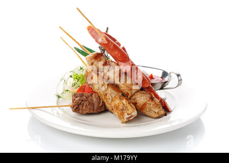 Das Essen im Restaurant. Lecker Mittagessen. Spieße und Würstchen mit Zwiebeln und frischer Tomatensauce auf Weiß Stockfoto