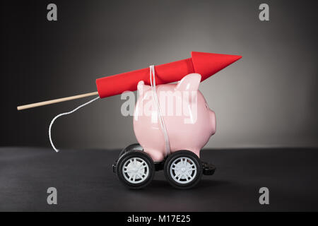 Red Rocket Feuerwerk Gefesselt mit Sparschwein auf schwarzem Hintergrund Stockfoto