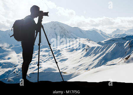 Silhouette eines Mannes mit Rucksack Fotografieren im Winter mit Stativ Stockfoto