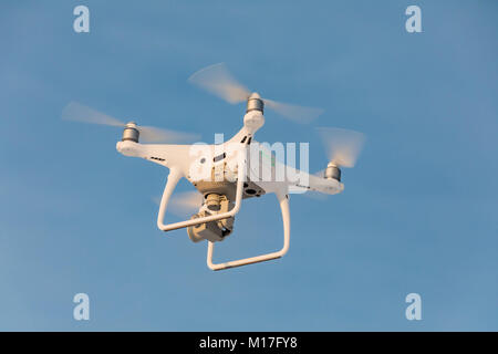 Fliegen weiß drone Phantom auf den blauen Himmel. Landung eines summten Hand mit drehenden Propellern Stockfoto