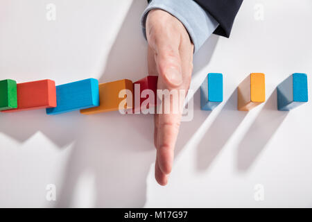 Hohe Betrachtungswinkel von Kaufmann stoppen Bunte Dominosteine fallen auf Schreibtisch Stockfoto