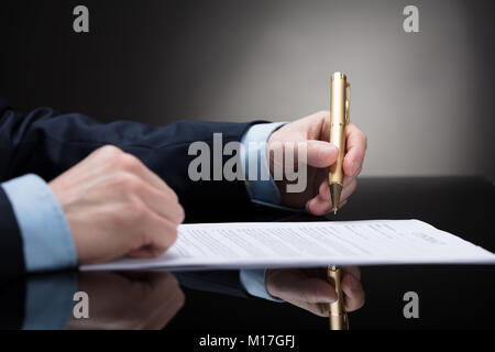 Nahaufnahme der Kaufmann Hand mit Stift auf Papier zu unterzeichnen Vertrag Stockfoto