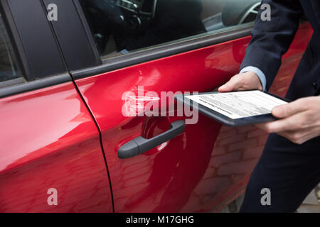 Rotes Auto in der Nähe der Person Hand mit digitalen Tablet Übersicht Versicherung Formular auf dem Bildschirm Stockfoto