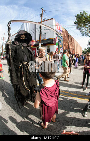 Atlanta, GA, USA - 21. Oktober 2017: ein Junge interagiert mit Person tragen bedrohliche Sensenmann Kostüm und Holding Scythe in Atlanta Halloween Parade. Stockfoto