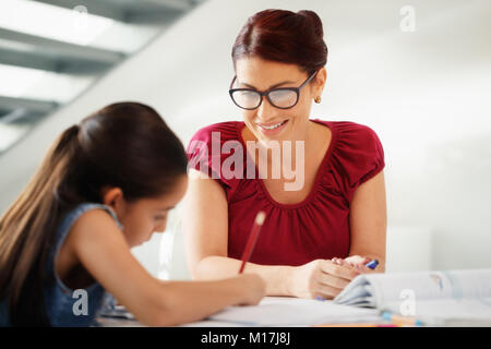 Bildung mit Mama hilft Tochter tun Schule Hausaufgaben zu Hause Stockfoto