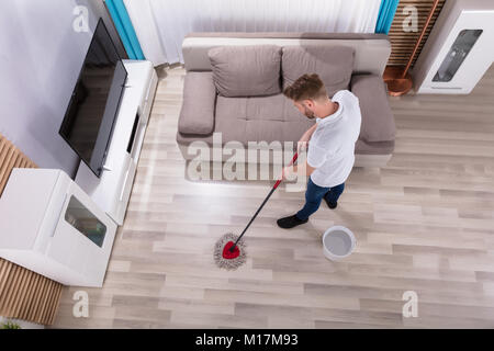 Junger Mann Reinigung Boden mit Mop zu Hause Stockfoto