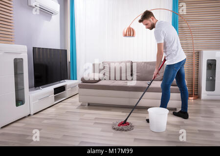 Junger Mann Reinigung Boden mit Mop zu Hause Stockfoto