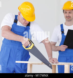 Arbeitnehmer arbeitet mit Handsäge, Polier auf Hintergrund Stockfoto