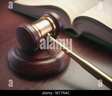 Holz Richter Hammer mit goldenen Details und eine Gesetzgebung Buch neben. Stockfoto