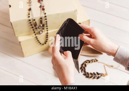 Weibliche Hände öffnen Sie den leeren Geldbeutel gegen Frauen Kleidung und Accessoires nach dem Einkaufen. Stockfoto