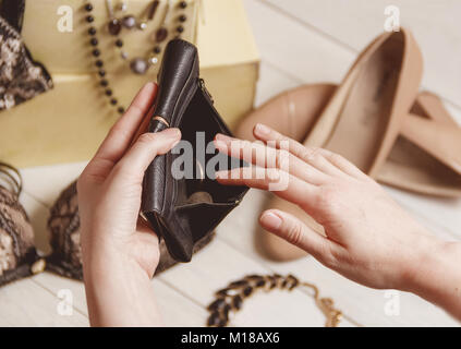 Weibliche Hände öffnen Sie den leeren Geldbeutel gegen Frauen Kleidung und Accessoires nach dem Einkaufen. Stockfoto