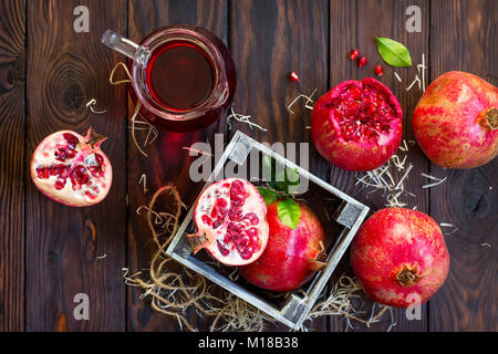 Frisch gepressten Fruchtsaft und reifer Granatapfel Granatapfel auf einem Holztisch. Das Konzept der Ernährung für Superfoods und Gesundheit oder Entgiftung. Stockfoto