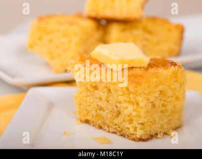 Stück frisch gebackenes Maisbrot mit cremiger Butter auf der Oberseite. Stockfoto