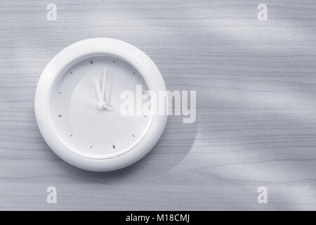 Weisse Uhr auf Holz Wand Hintergrund mono Farbton Stockfoto