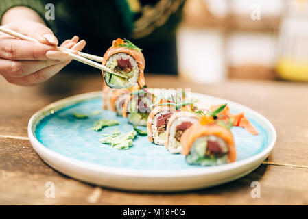 Männliche Person isst Sushi Rollen mit Stäbchen, japanische Küche. Traditionelle asiatische Speisen, Meeresfrüchte lecker Stockfoto