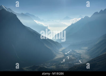 Majestätischen Blick auf die Silhouetten der Berge und niedrige Wolken bei Sonnenuntergang in Nepal. Landschaft mit hohen Felsen der Berge des Himalaja, schönen blauen Himmel und Stockfoto