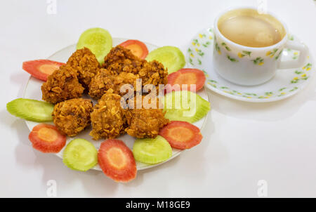 Knusprig frittierte Hühnchen pakora garniert mit geschnittene Karotten und Gurken serviert Snacks mit Tee. Eine beliebte Nicht veg indisches Essen serviert wird als Start Stockfoto