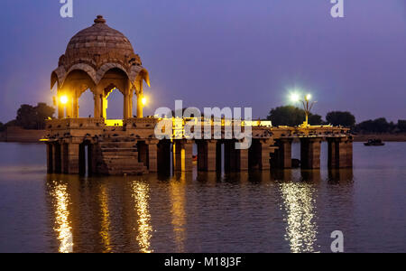 Gadi Sagar (See Gadisar) Jaisalmer mit Nachtbeleuchtung und Touristen mit einem Boot fahren. Stockfoto