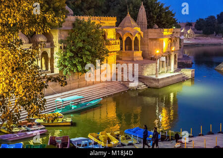 Gadi Sagar (See Gadisar) Jaisalmer mit Nachtbeleuchtung und Touristen mit einem Boot fahren. Stockfoto