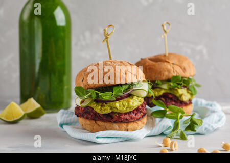 Vegan Zuckerrüben Burger mit Gemüse, Guacamole und Roggen Brötchen mit grünen Saft. Gesunde vegane Ernährung Konzept. Stockfoto