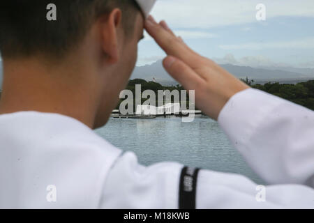 PEARL HARBOR NAVAL BASE, HI - ein Seemann mit dem Amerika Amphibious Ready Gruppe an Bord amphibisches Schiff USS America (LHA 6) begrüßt, da sie das USS Arizona Memorial verlassen, Jan. 25, 2018. Manning der Schienen ist ein Naval Tradition jede Bereitstellung von Schiff führt und ist eine Methode der ehrenkompanie oder Rendering Ehren durch Marineschiffe verwendet. Die 15. MEU und Amerika ARG sind derzeit auf eine Routine für sieben Monate, um die Bereitstellung zu den USA 3., 5. und 7 Flotte Bereiche des Betriebes als Reaktion auf Krisen und Kontingenz Kraft eingesetzt. (U.S. Marine Corps Stockfoto