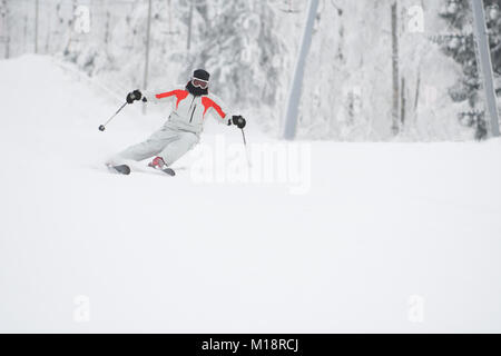 Alpine Skifahrer Skifahren bergab über weißen Schnee Hintergrund Stockfoto