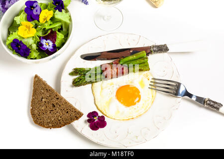 Ei mit Spargel und Schinken auf einer mediterranen Stil serviert mit Salat und essbaren Blüten Stockfoto