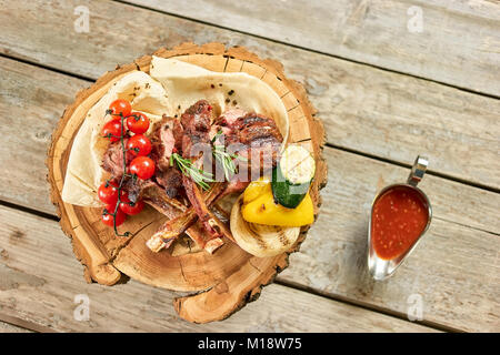 Draufsicht auf Teller mit gebratenem Lamm Rippen mit Tomaten und Soße. Stockfoto