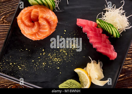 Gerollten frischen Lachs und Thunfisch in Scheiben geschnittene Stücke Nahaufnahme. Stockfoto