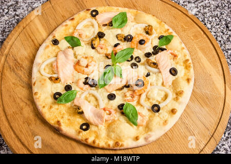 Pizza mit Meeresfrüchten, Oliven und Basilikum. Stockfoto