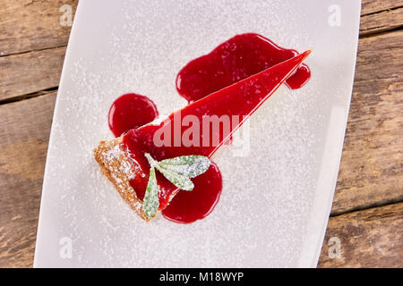 Stück Käsekuchen mit süßen roten Marmelade auffüllen und Mehl. Stockfoto