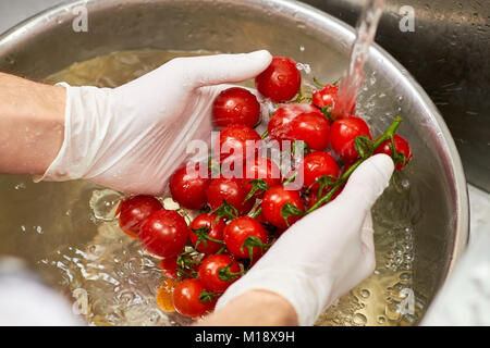 Koch Hände halten Dampf verbunden Cherry Tomaten. Stockfoto