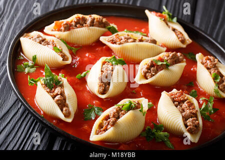 Italienische Küche: conchiglioni Nudeln mit Hackfleisch mit grünen in Tomatensoße schließen gefüllt - bis auf die Platte auf dem Tisch. Horizontale Stockfoto