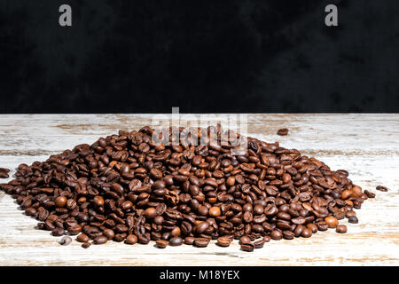 Geröstete Kaffeebohnen auf einem alten Holztisch. Grauer Hintergrund. Freier Platz für Text oben. Stockfoto