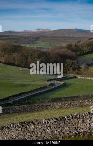 Die Straße schlängelt sich durch die Yorkshire Dales in der Nähe von Horton In Ribblesdale. Auf der Rückseite ist Ingleborough. Stockfoto