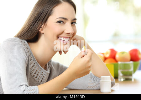 Porträt einer Frau, die eine gelbe Vitamin Pille und bei Ihnen zu Hause Stockfoto