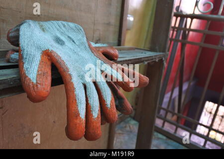 Einen gebrauchten Industrie Gummi palm Handschuhe sitzen auf einem alten woody Möbel. Stockfoto