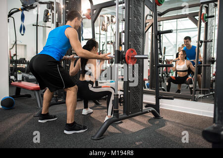 Fitnessraum Kursleiter helfen, junge Frau Stockfoto