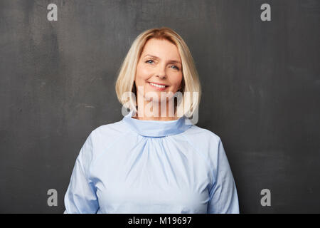 Close-up Studio shot eine schöne ältere Frau in T-Shirt und dunkler Hintergrund stehen und lächelte. Stockfoto